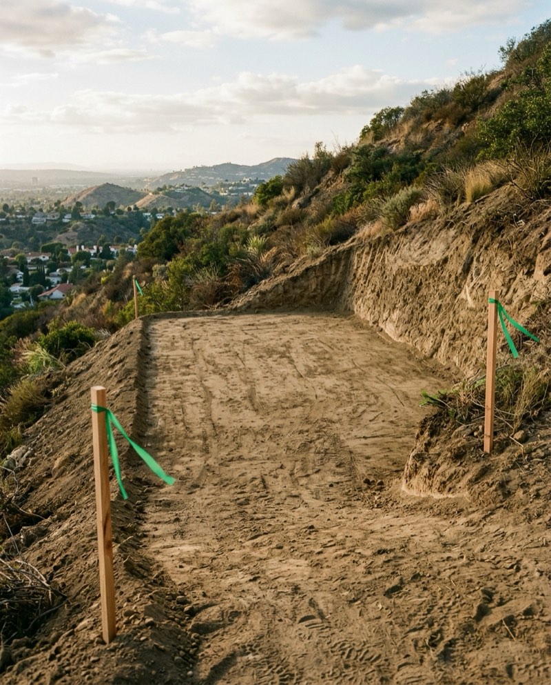 Level compacted building pad with grade stakes on a hillside lot